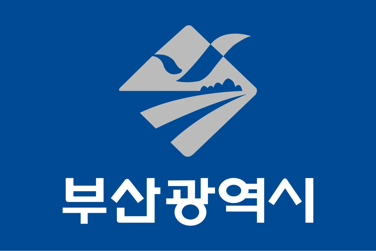 Bandera blava de Busan de 1995 amb un rombe gris que dibuixa una gavina i el nom en hangul